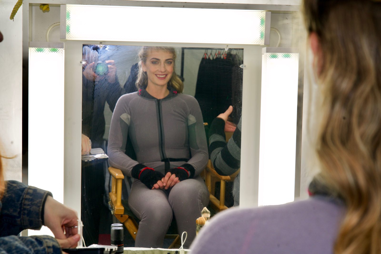 Emily Riedel in a motion-capture suit seen in a makeup mirror