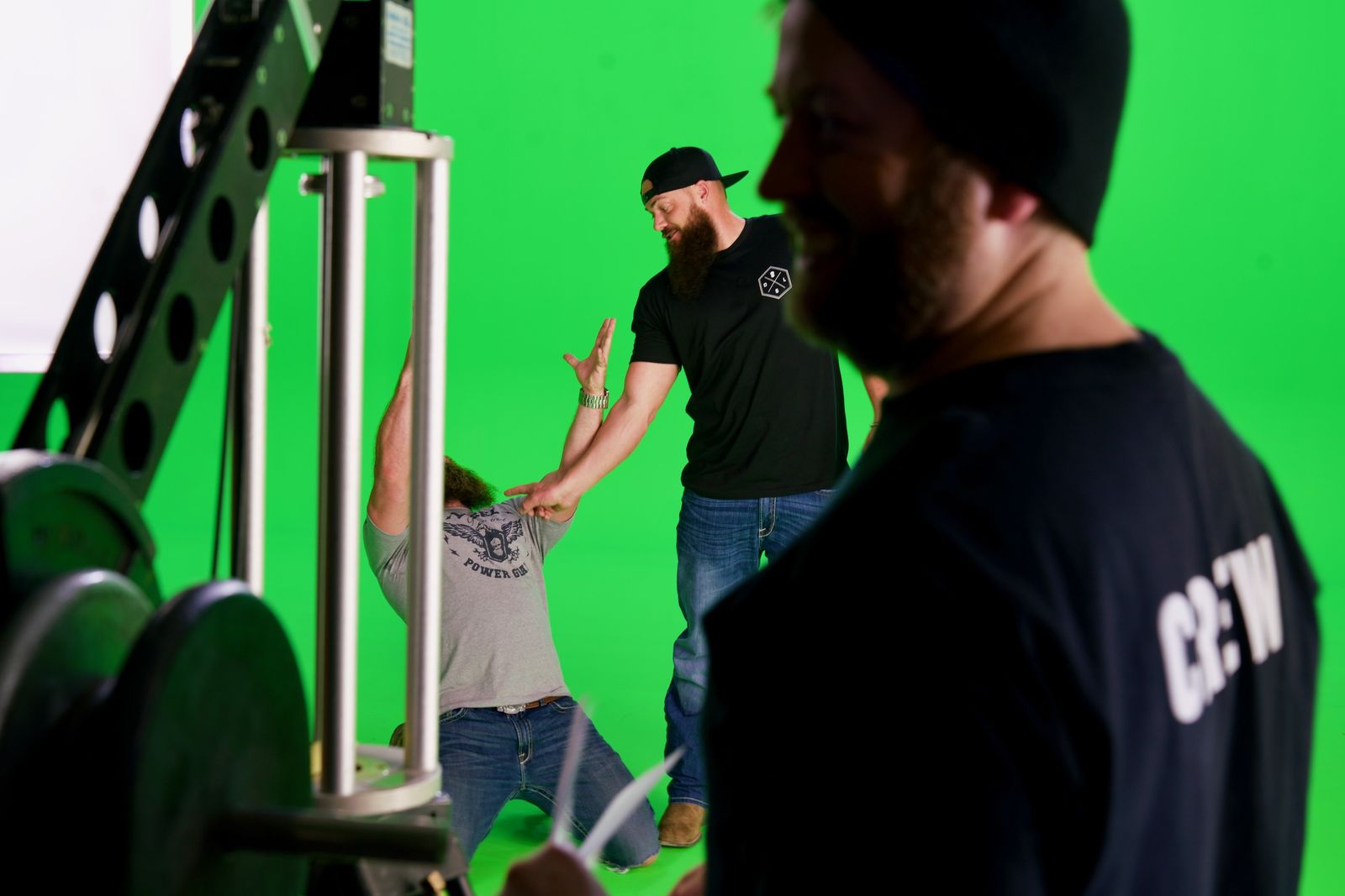 Crew working on the green screen stage beside a metal truss