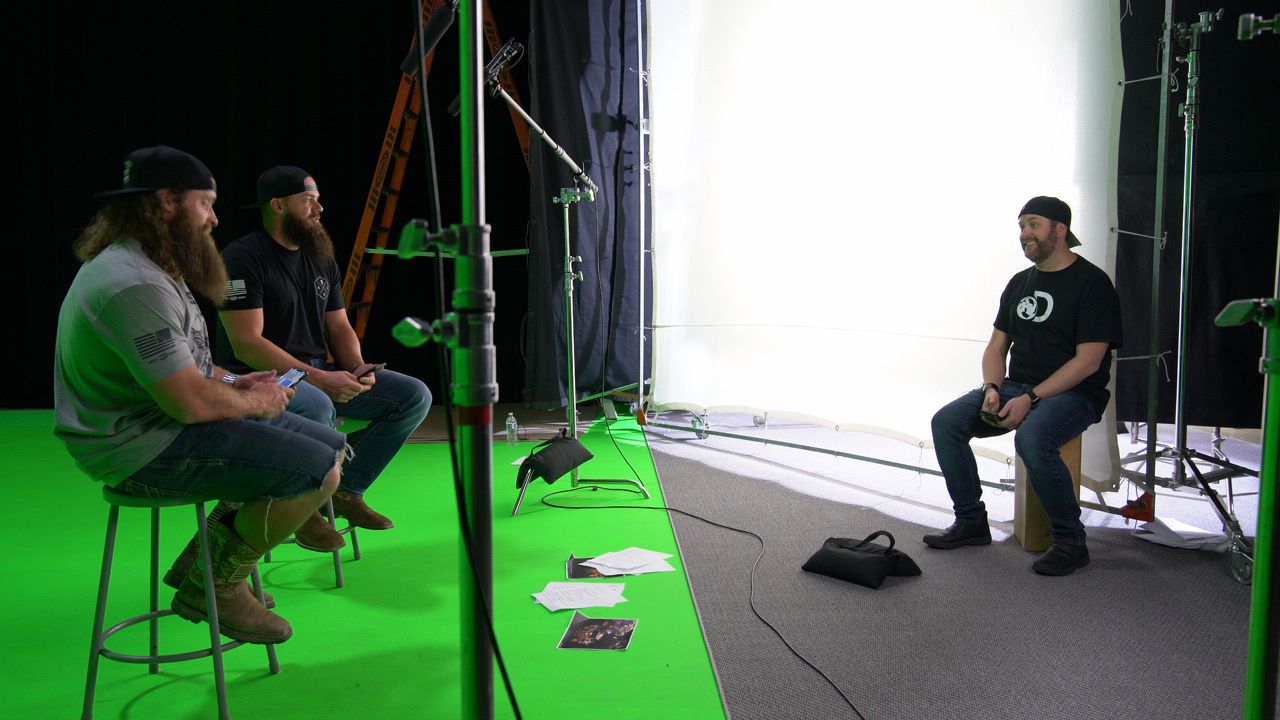 Heavy D and Diesel Dave on stools on a green screen stage as crew sets up