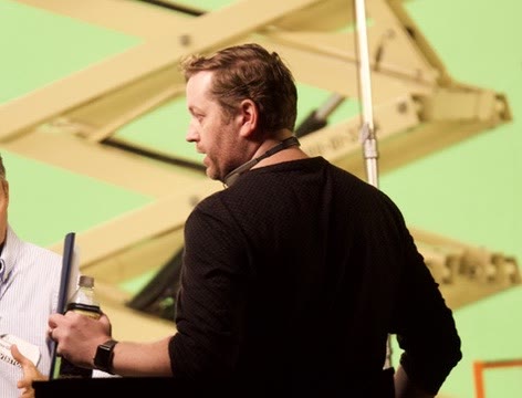 John Davidson on set with script in hand, directing the crew