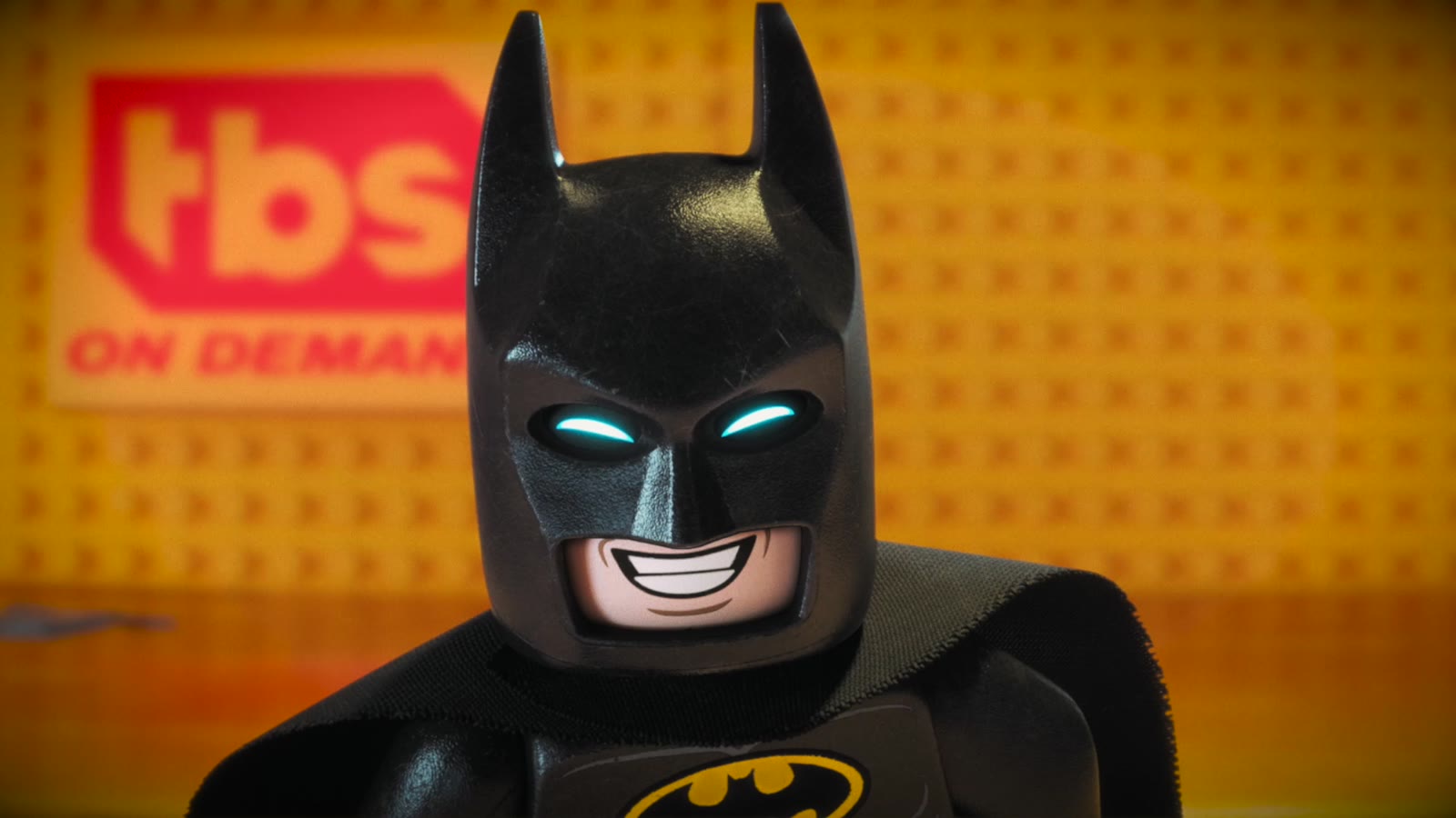 Close-up of a grinning Lego Batman in front of the TBS On Demand logo
