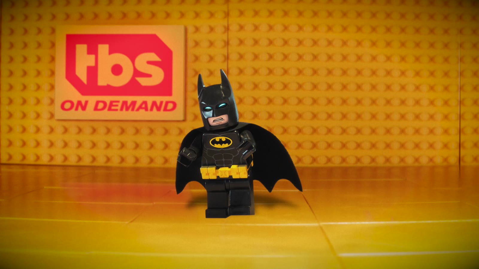 Lego Batman standing in front of a TBS On Demand logo on a yellow LEGO-brick set